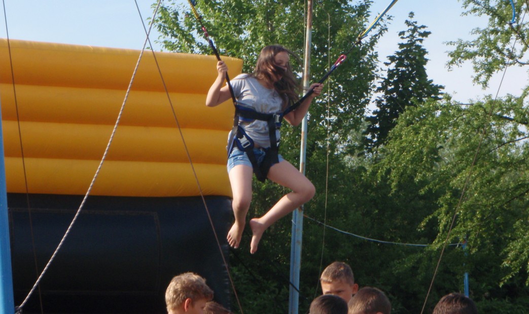 Dzieci bawiące się na trampolinach z asekuracją